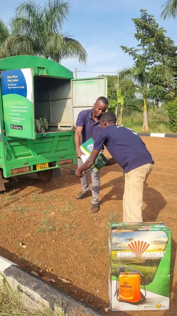 Two EzyAgric staff unload an order from a green EzyAgric delivery van, with a boxed knapsack sprayer waiting on the ground